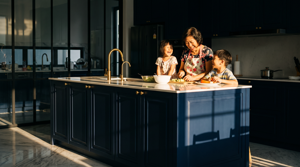 Multigenerational Malaysian family cooking together at a navy kitchen island in a bungalow