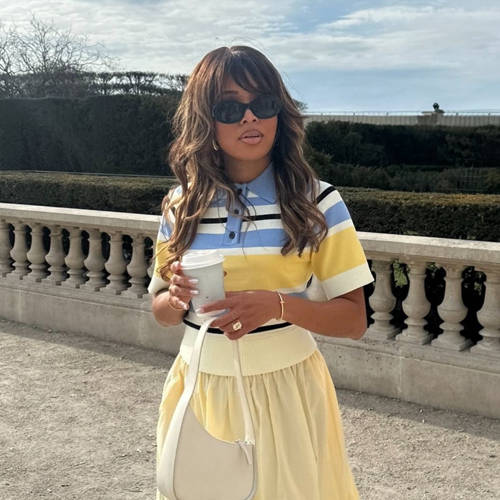 Person standing outdoors wearing a casual outfit, hair cut in a layered style avoiding a traditional short cut or bob.