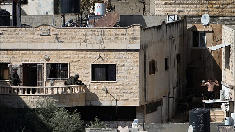 A man holds his hand while in the sight of two Israeli soldiers in the West Bank town of Qabatiya during a raid, Thursday, Sept.19, 2024. (AP Photo/Majdi Mohammed)