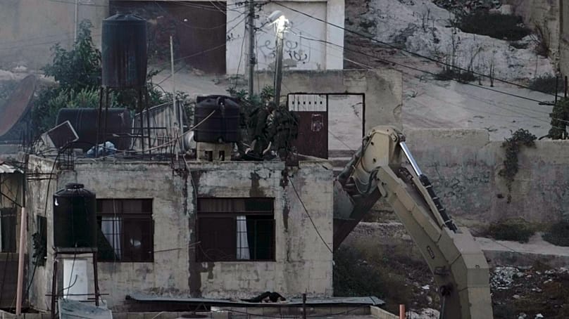 Israeli soldiers look over a rooftop where two lie motionless in the West Bank town of Qabatiya during a raid, Thursday, Sept.19, 2024. (AP Photo/Majdi Mohammed)