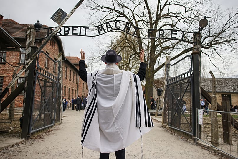 A man stands in front of the Auschwitz entrance prior to the annual 