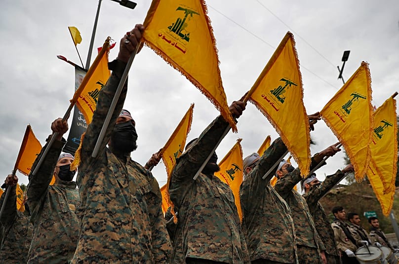 Hezbollah fighters hold their group's flag in a southern suburb of Beirut, 4 January, 2022
