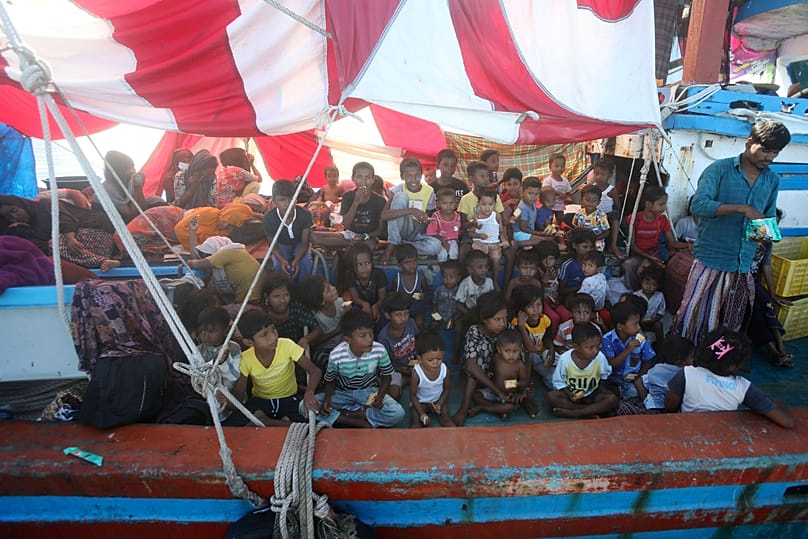 Rohingya children wait for food supply delivered by local fishermen on their boat anchored in the waters near the coast of Labuhan Haji, 22 October, 2024