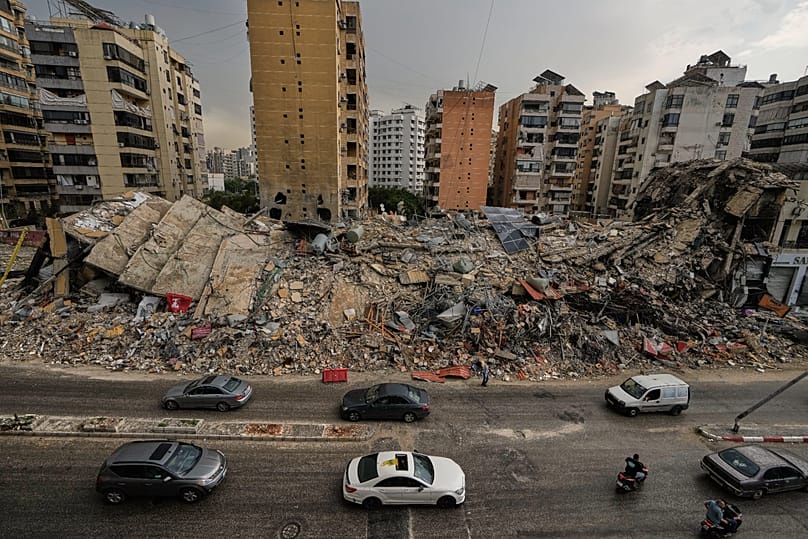 Residents drive past the rubble of destroyed buildings in Dahiyeh, 17 April, 2026