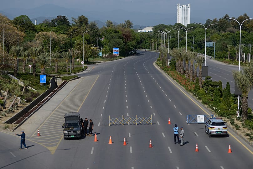 Police officers stand guard at a checkpoint on a barricaded road to ensure security ahead of the second round of the US-Iran talks, in Islamabad, Sunday, April 19, 2026