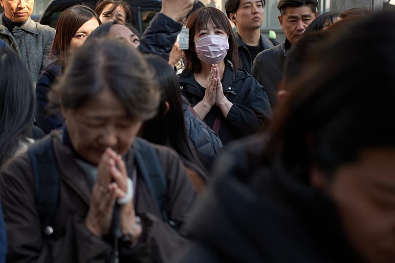 Bystanders pray as Japan marks 15th anniversary of the 2011 earthquake, tsunami, and nuclear disaster that devastated the northeastern coast, Tokyo, March 11, 2026 in Tokyo, 