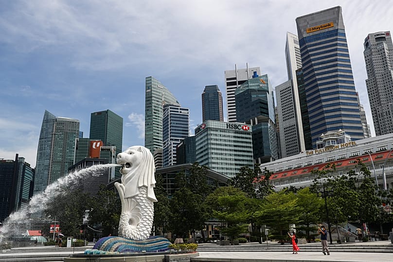 People walk in front of the financial skyline in the Marina Bay area in Singapore, 30 June, 2020