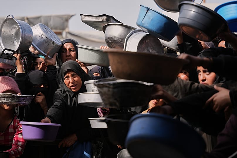 Palestinian women receive donated food at a community kitchen in Nuseirat, in central Gaza Strip, Saturday, Jan. 24, 2026.