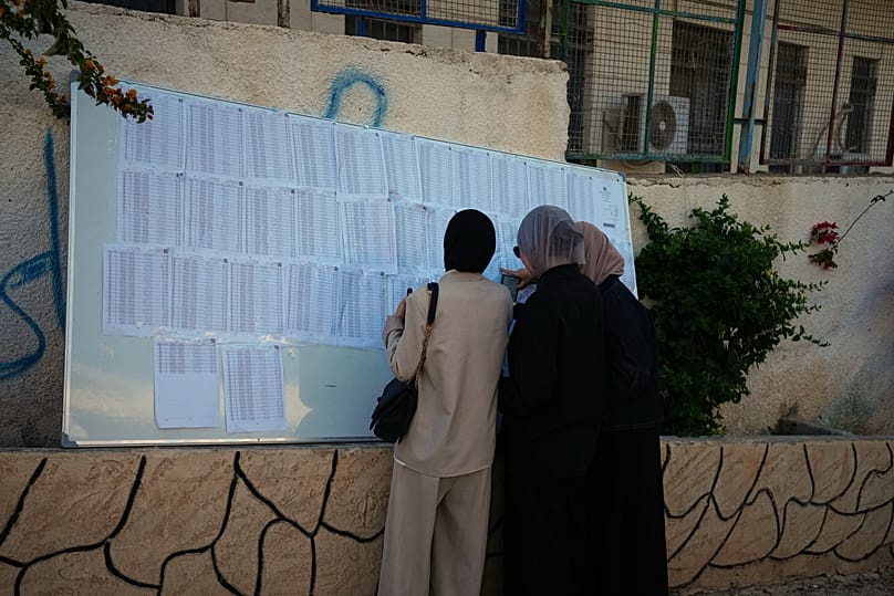 Palestinian women search for their names on a voter list to take part in local elections in Al-Ubaidiya, West Bank, Saturday, 25 April, 2026.