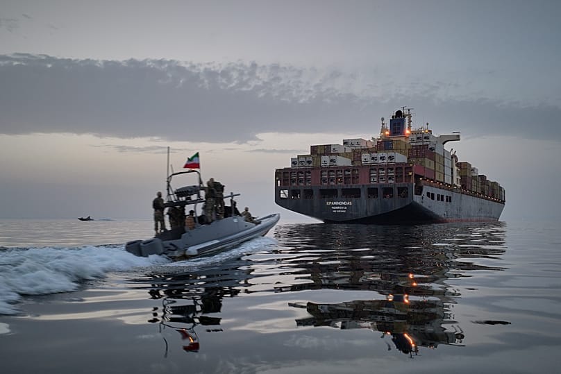 An Iranian Revolutionary Guard speedboat approaches a cargo vessel in the Strait of Hormuz.