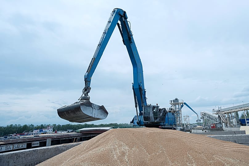 An excavator loads grain into a cargo ship at a grain port in Izmail, 26 April, 2023