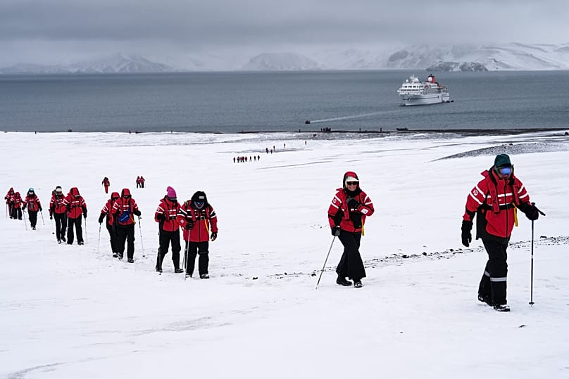 Passengers walk inside the volcano at Deception Island in Antarctica, Wednesday, Nov. 26, 2025.