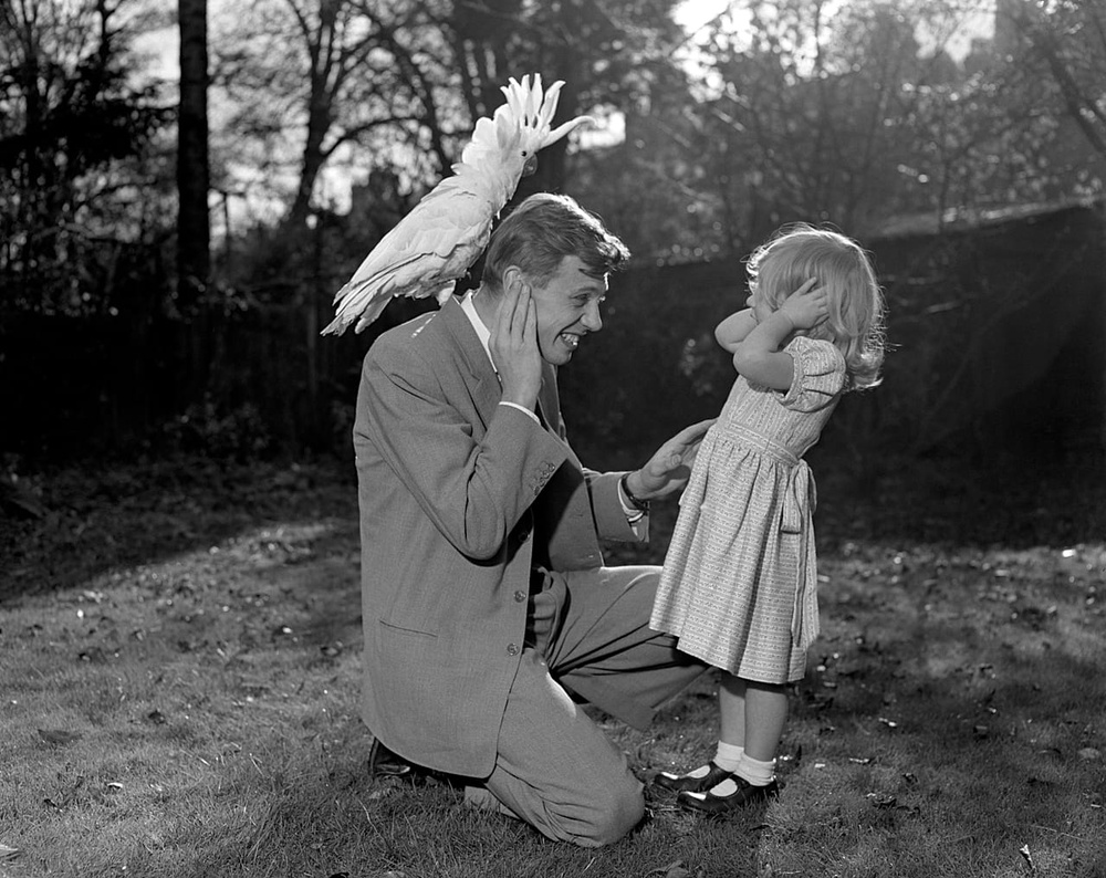 Three year old Susan and her father David Attenborough pose for a photo with a sulphur-crested cockatoo Georgie, 7 December 1957.