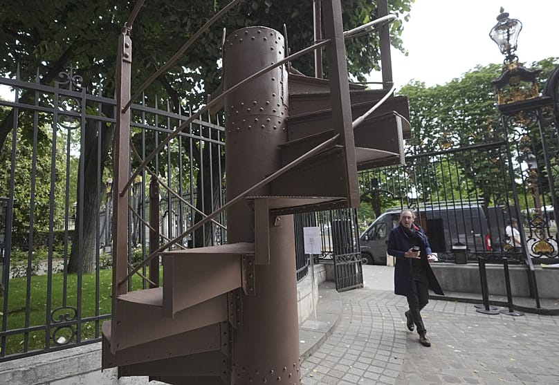 A man walks past a section of the original spiral staircase of the Eiffel Tower, dating from 1889, at the Artcurial auction house in Paris, on Wednesday 13 May 2026
