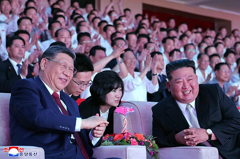 North Korean leader Kim Jong Un and Chinese President Xi Jinping smile as they watch welcome performance at Pyongyang Gymnasium in Pyongyang, Monday, June 8, 20
