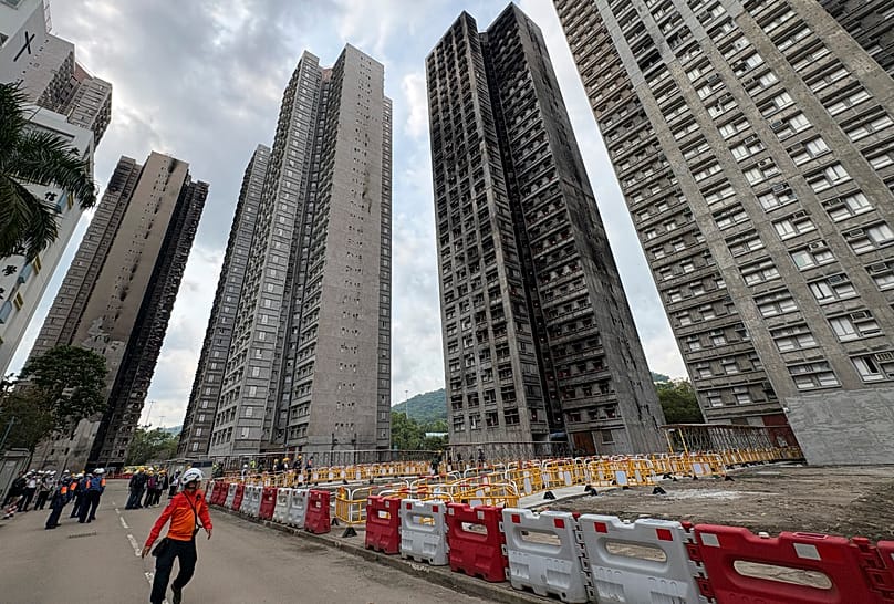 A worker walks by the remaining shell of the buildings of Wang Fuk Court in Hong Kong, 22 April, 2026