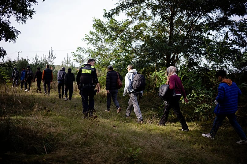 FILE - Police officer escorts a group of migrants who illegally crossed the border from Poland into Germany, southeast of Berlin, Germany, on Oct. 11, 2023