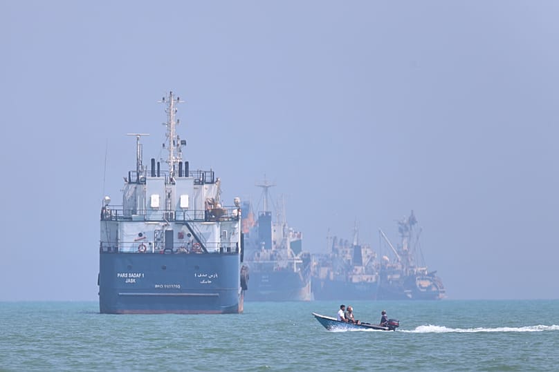 A small motorboat passes anchored vessels in the Strait of Hormuz off Bandar Abbas, Iran, Thursday, June 11, 2026.