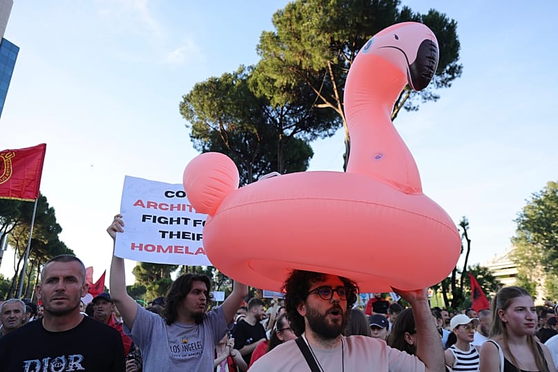 A protester carries a flamingo pool float during a rally in Tirana, Saturday, June 13, 2026.