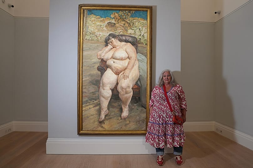 Sue Tilley, a model for British painter Lucian Freud, poses in front of Freud's painting of her, titled 