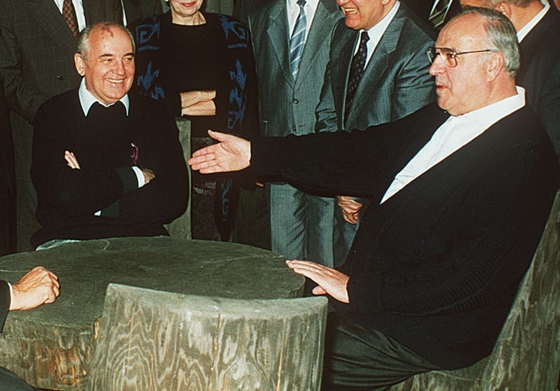 Soviet President Mikhail Gorbachev, left, talking with West German Chancellor Helmut Kohl, right, at a table in the garden of the guest house in Archiz in this July 17, 1990 