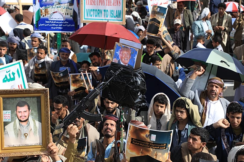 Houthi supporters raise a poster of their leader Abdul Malik al-Houthi and a poster criticising President Donald Trump during a rally in Sanaa, 16 June 2026
