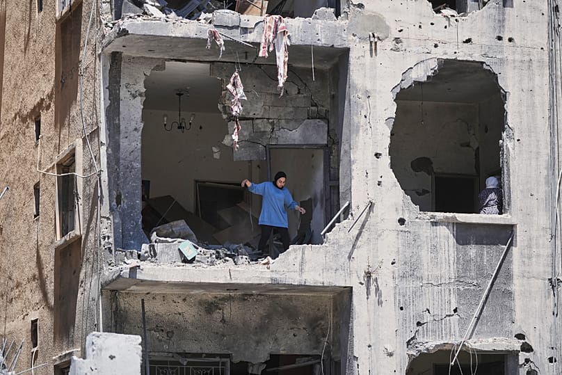 A woman walks through her apartment damaged in Israeli strikes in the southern port city of Tyre, 18 June 2026