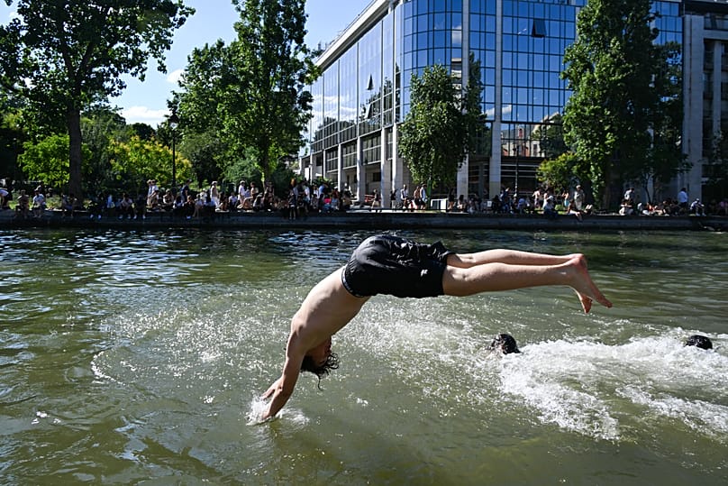 A boy dives into the Canal Saint-Martin in Paris, on Wednesday, June 17, 2026, the first day of opening for authorized bathing in the canal.