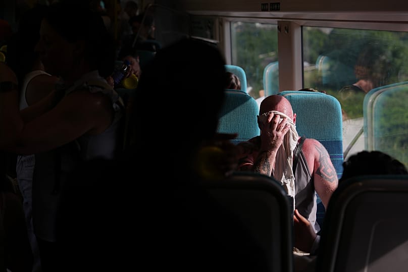 A man on a train wipes sweat from his face on a hot day in London, 24 June, 2026