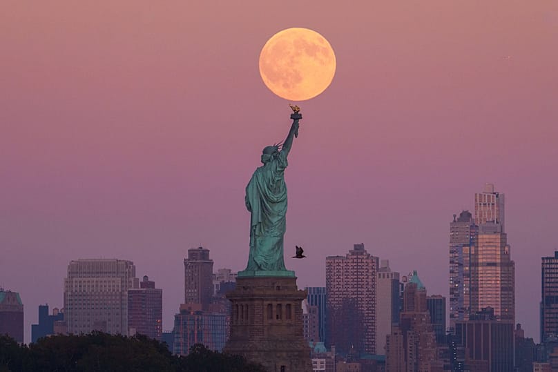 ARCHIVES - The harvest supermoon rises behind the Statue of Liberty and the Brooklyn skyline on 6 October 2025, in Jersey City, New Jersey.