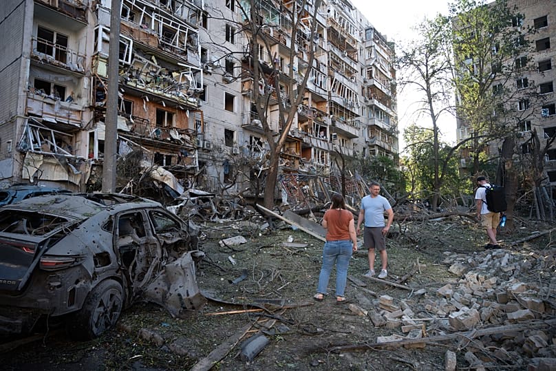 People look at a residential building damaged during the Russian missile attack in Kyiv, 2 July, 2026