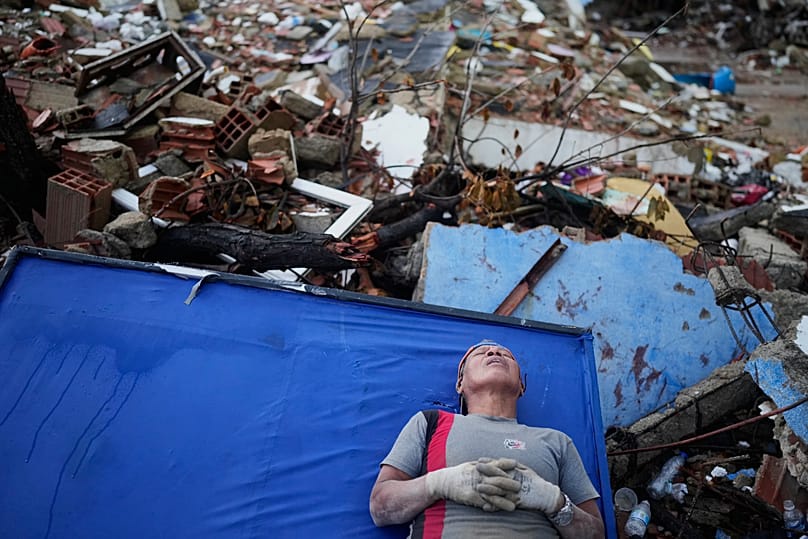 Resident Kerli Faria takes a break amid the rubble while searching for her nephews at a building that collapsed during the earthquakes that struck La Guaira, Venezuela
