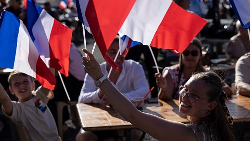 People wave French flags during a rally attended by far-right party National Rally president Jordan Bardella and far-right leader Marine Le Pen in Lievin, 4 July, 2026