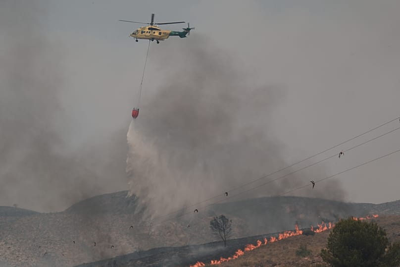 A helicopter drops water while fighting a wildfire in Los Gallardos, near Almeria, Spain, Friday, July 10, 2026.