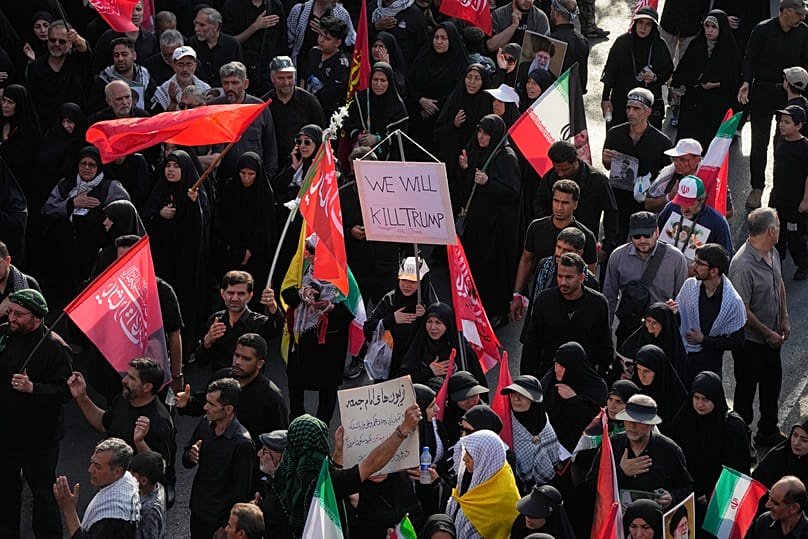 A mourner carries a sign reading 