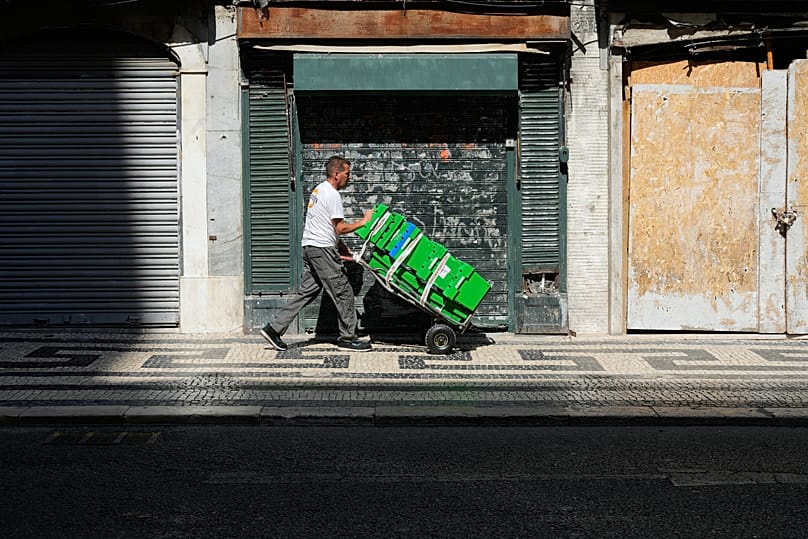 A worker carrying boxes walks in the sun in Lisbon, Portugal, where the temperature has risen sharply and the authorities have issued a warning for a prolonged heatwave.