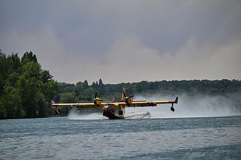 A Canadair water bomber scoops up water from the Seine River while fighting wildfires in the Fontainebleau forest region, France, Monday, July 13, 2026. 
