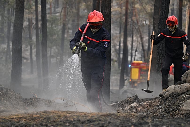 A firefighter sprays water after a wildfire in the region of the Fontainebleau forest, south of Paris, France, Tuesday, July 14, 2026. 