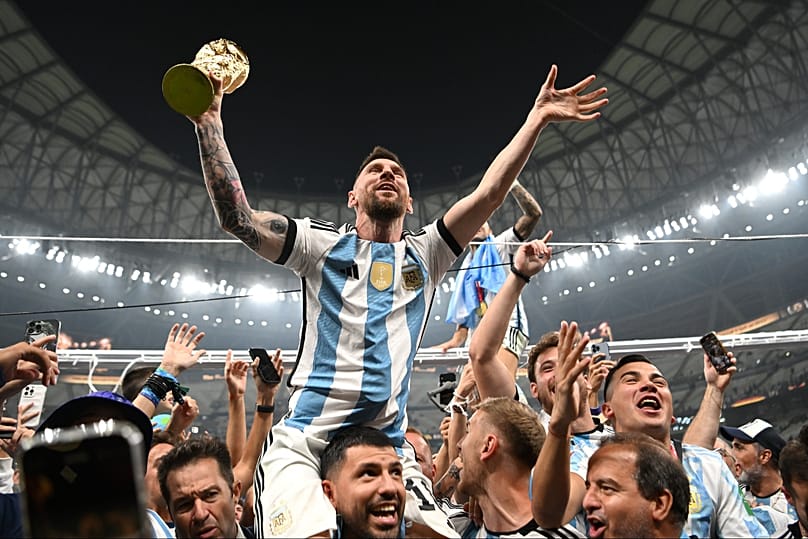 Lionel Messi with the FIFA World Cup Qatar 2022 trophy on the shoulders of former teammate Sergio Aguero after Argentina beat France in the final, 18 Dec 2022