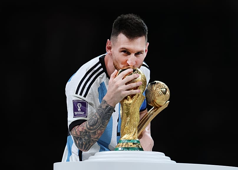 Sealed with a kiss: Lionel Messi embraces the FIFA World Cup trophy while holding the Adidas Golden Boot award after the final against France, 18 September 2022, Saudi Arabia