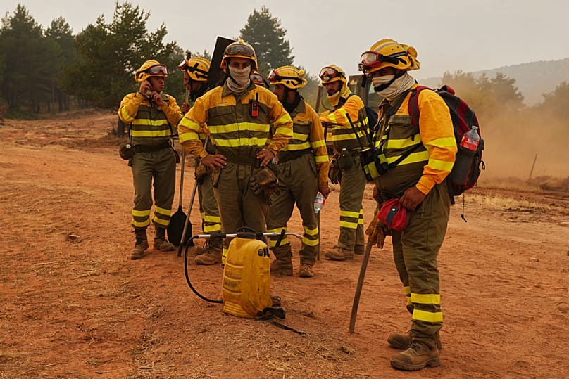 Forest rangers take a break before returning to work on the fire near Condemios de Arriba, Guadalajara province, Spain, Wednesday, July 22, 2026.