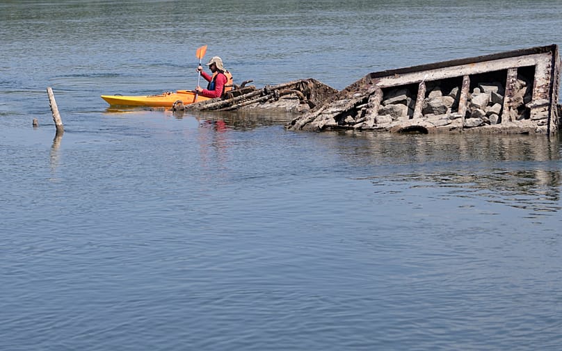 Canoeist passes the wreck of a German Second World War warship on the Danube near Prahovo in Serbia, 29 August 2022