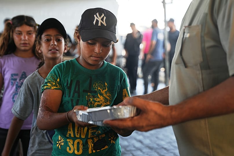 Displaced Palestinian children lineup to receive donated food at a community kitchen in Khan Younis, southern Gaza Strip, Thursday, July 23, 2026