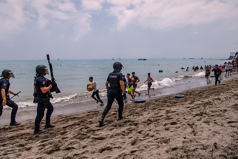 Spanish police officers respond as migrants cross from Morocco into the Spanish enclave of Ceuta, Thursday 30 July 2026. (AP Photo/Antonio Sempere)