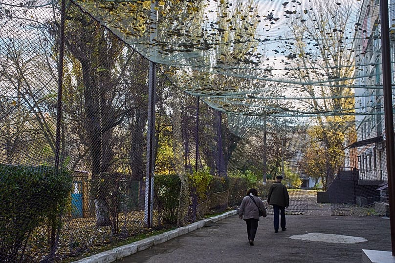 FILE: Local residents walk along a street covered with an anti-FPV-drone net in the frontline city of Kherson, Southern Ukraine, Monday, Nov. 3, 2025.