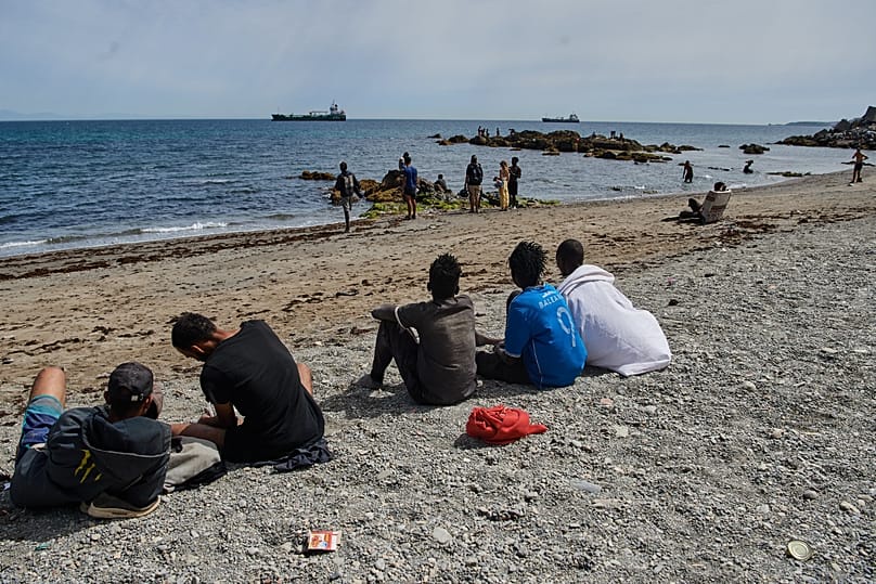 Migrants who crossed into Spain from Morocco gather on a beach in the Spanish enclave of Ceuta, Monday, Aug. 3, 2026.