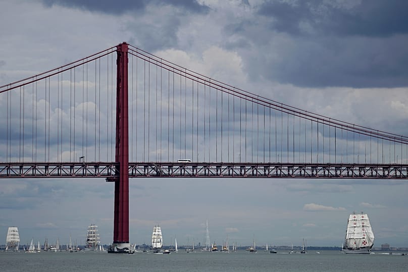 The training ship Sagres, on the right, leads a parade of large sailing ships on the Tagus, with the 25 April Bridge in the background, in Lisbon, on 3 September 2023