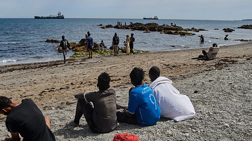 Migrants who crossed into Spain from Morocco gather on a beach in the Spanish enclave of Ceuta, Monday 3 August 2026. (AP Photo/Antonio Sempere)