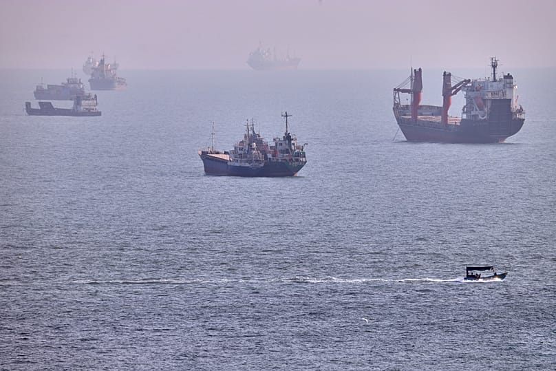 A small boat sails past cargo ships and other commercial vessels anchored in the Strait of Hormuz off Bandar Abbas, Iran, Wednesday, Aug. 5, 2026.
