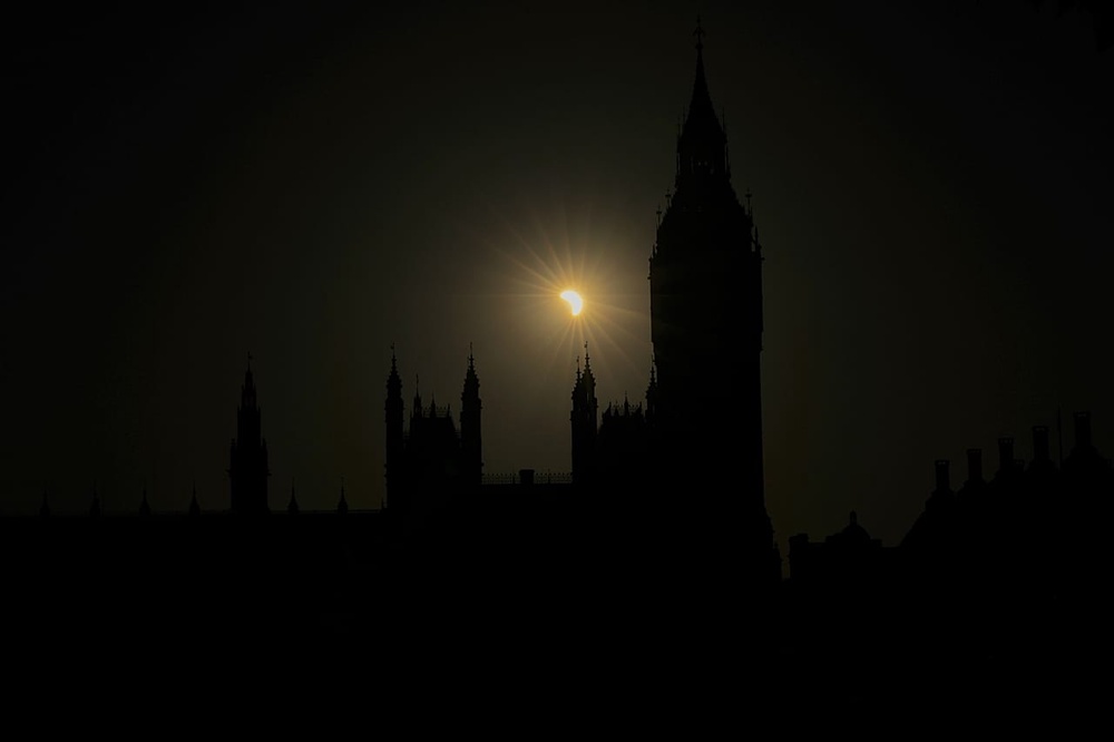A partial solar eclipse is seen above the Houses of Parliament in London